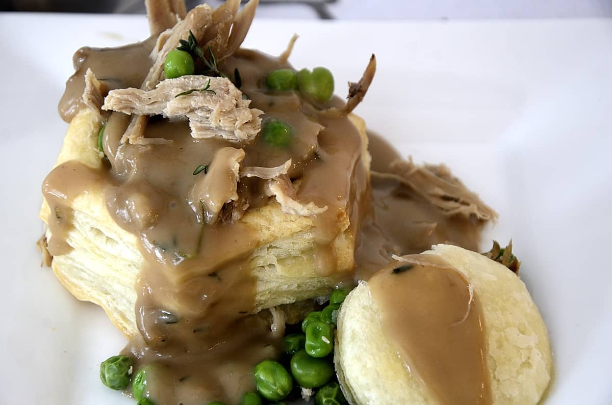 Leftover turkey bits in a puff pastry shell with Turkey Marsala Gracy drizzele over it and peas on the side.