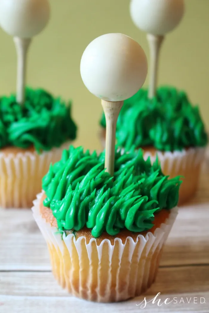 Cupcakes with green shaggy icing for grass, a tee in themiddle and a golf ball perched on the tee.