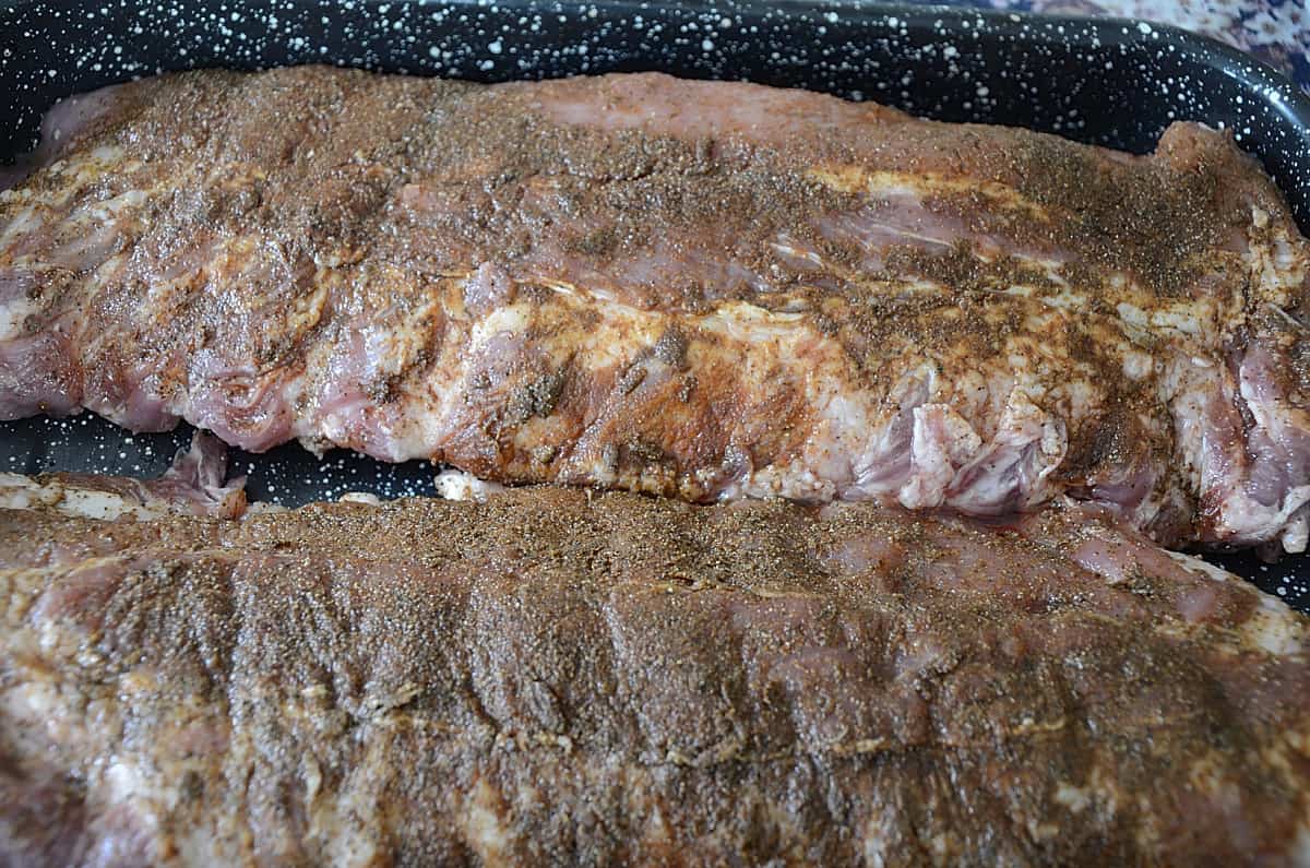 RAck of back ribs with dry rub in a pan.