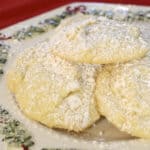 Fluffy white chocolate chip snowball cookies dusted with icing sugar on a Christmas plate.