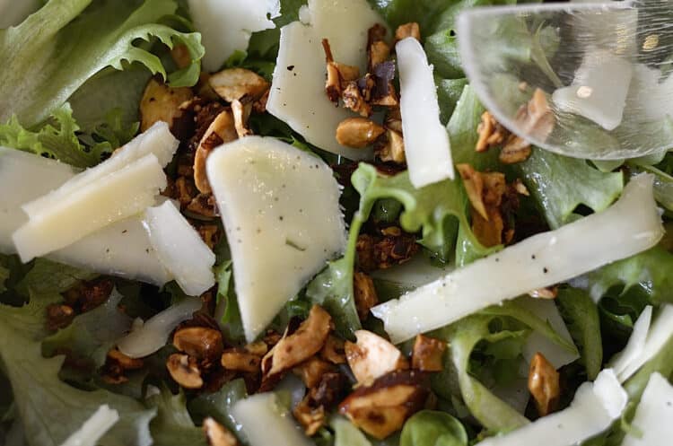 Close up of Almond and asiago salad in a bowl drizzled with dressing.