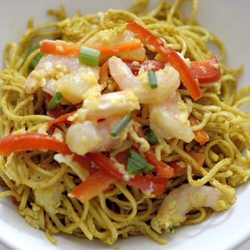 Curried Singapore Noodles with shrimp and red peppers in a bowl.