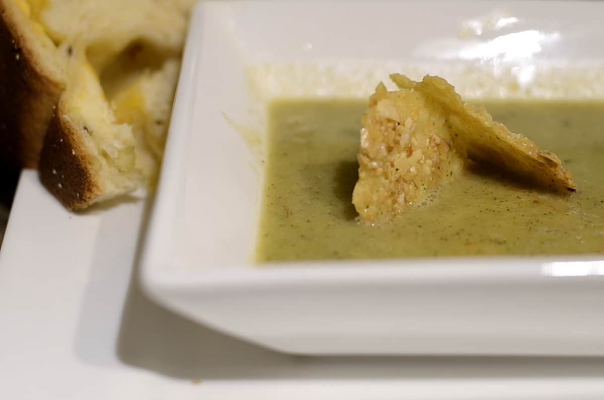 Healthy Zucchini Soup in a bowl garnished with parmesan/almond wafers.