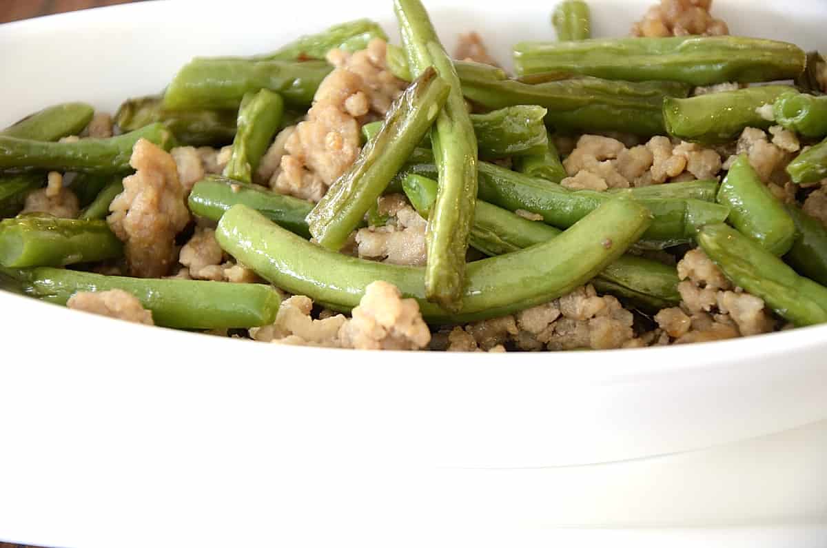 Schezuan fried green beans with ginger ground pork in a dish.