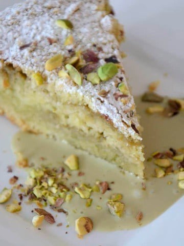 Piece of Italian crumb cake with pistachio cream filling, topped with crushed pistachios and icing sugar.