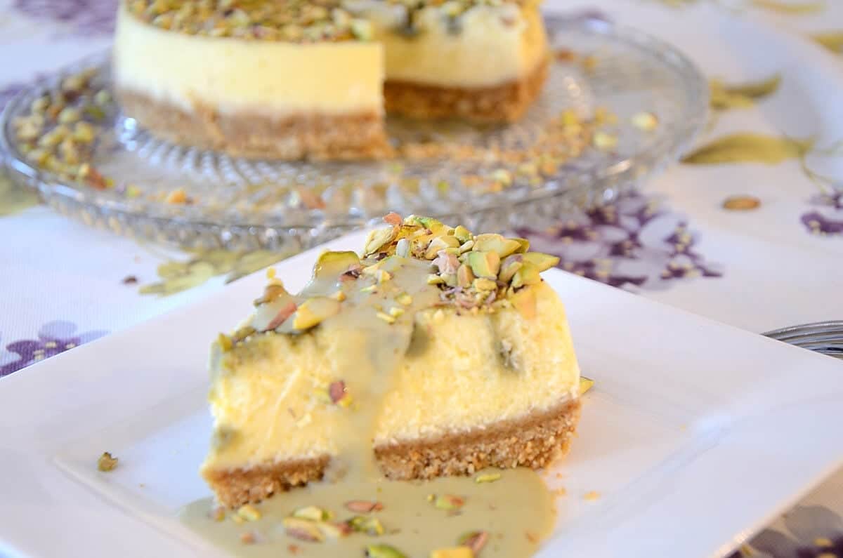 Slice of pistachio cheesecake drizzle with pistachio cream and crushed nuts.