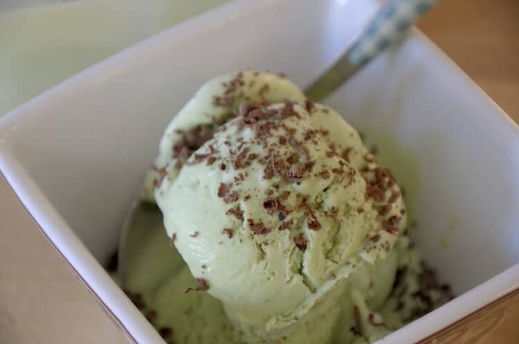 Bowl of creamy pistachio ice cream sprinkled with chocolate.