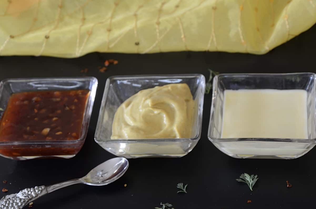 Trio of sauces including General Tso, Curry Mustard Mayonnaise and Champagne Aioli in small dishes.