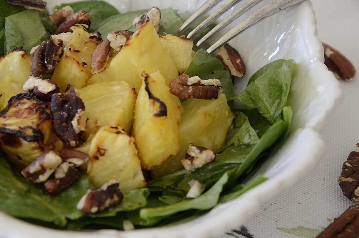 Grilled pineapple chunks on a bed of spinach with toasted pecans.