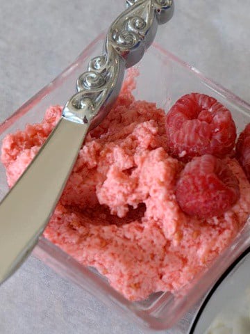 Raspberry butter in a small dish with a spreader.
