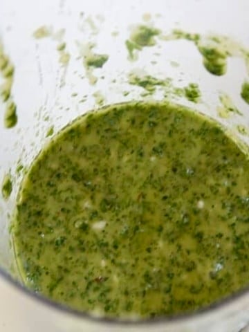 Close up of bright, green chimichurri sauce in a blender cup.