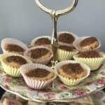 Pecan tassies in a frilly paper cup on a tiered tea plate.