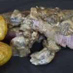 Beef tenderloin medallion on a plate with Steak Diane cream sauce on it.