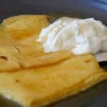 Folded crepes on a plate with Crepe Suzette sauce.