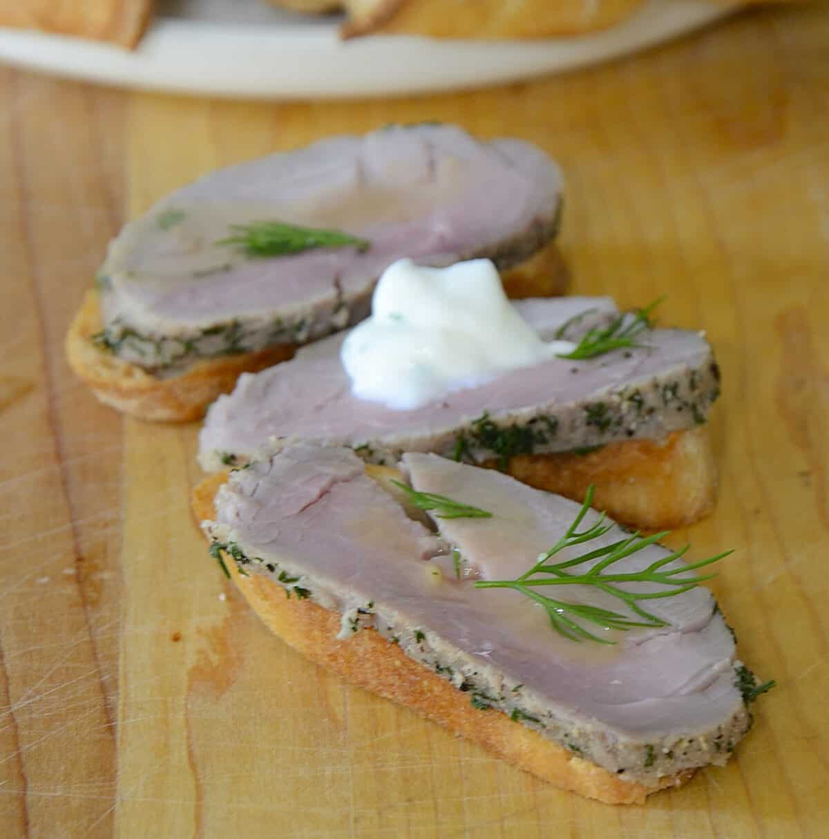 Slices of dill cured pork tenderloin garnished with mustard sauce.