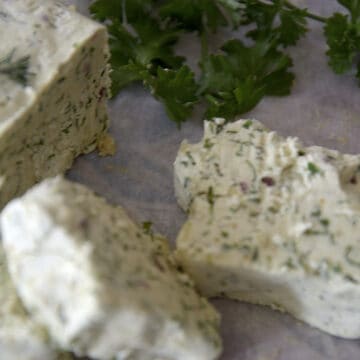 Close up of slices of Cafe de Paris butter on parchment.